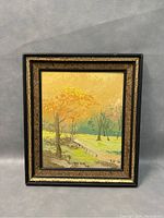 Front view of the framed oil painting showing the autumn landscape scene with trees, a stone wall, and a pathway.