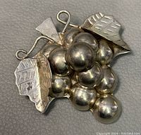 Front view of the sterling silver brooch showing grape cluster and leaves design.