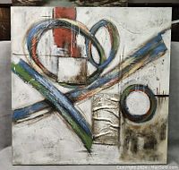 Full view of large abstract canvas print with geometric shapes and textured elements in red, blue, green, white, and beige.