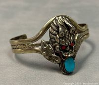 Close-up of the dragon head design on the cuff bangle highlighting the turquoise and coral stones.