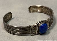 Front angle showing lapis lazuli stone set on ribbed silver cuff bracelet with ornate silver details.