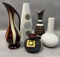 Front view of all five vintage ceramic items including Royal Dux pitcher and assorted vases showing designs and shapes
