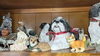 Shelf display showing various dog, cat, and animal figurines including a Shih Tzu with red bow and orange cat.