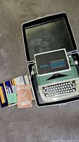 Royal Precision Portable typewriter in open black hard carrying case, with instruction manuals and booklets displayed to the side.