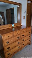 Front view of honey oak dresser with three small top drawers and six larger drawers underneath, matching wood-framed mirror attached