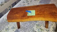 View of wood slab bench showing smooth natural wood surface and four round legs.