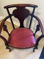 Top angled view showing carved wooden back and red velvet seat with brass trim