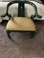 Front view of green lacquered horseshoe-style armchair with gold patterned upholstery