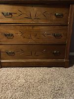 Front view of antique dresser showing three carved drawers with original metal handles and visible keyholes.