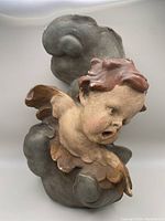 Front angled view of the cherub stone wall decor showing cherub's facial expression and cloud base