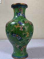 Full view of the green copper cloisonne enamel vase showing floral patterns and brass rims.