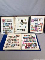 Four binders open to pages showing a variety of international stamps from different countries and eras.
