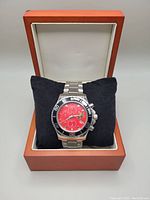 Full view of the RCMP stainless steel wristwatch inside a wooden watch box on a black pillow.