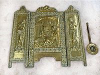 Overall view of the vintage repousse embossed brass fireplace screen with three panels and accompanying small brass item.