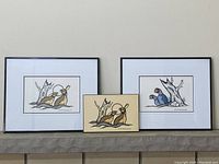 Three artworks displayed side by side on mantel