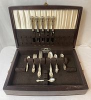 Full open wooden case showing silver plated flatware organization with satin lining inside lid and felt lining in base.