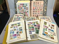 Overview photo showing six binders open and filled with various stamp collections including Canadian and international stamps on album pages.