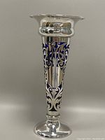 Full front view of silver vase showing filigree design over blue glass insert