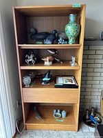 Frontal view of the teak shelf showing three shelves, a drawer, and various decorative items (not included). The shelf includes additional divider pieces for the top shelf.