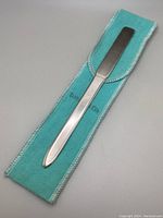 Full-length view of letter opener resting on turquoise pouch