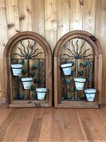 Full view of both decorative wall planters side by side, showing wooden frame, metal vine design and attached ceramic pots.