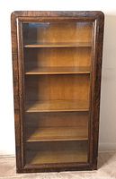 Full view of the wooden bookcase with glass door showing four wooden shelves inside.