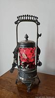 Side view of antique Victorian pickle castor with ruby red hand-painted art glass and ornate silver-plated handle and base