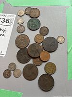 Multiple old British coins and tokens laid out on a surface, showing variety of sizes and designs including large copper and smaller silver coins.