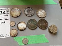 Overview photo of 12 Canadian coins including silver dollars, 50 cent pieces, and smaller denomination coins in various conditions.