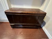 Front view of closed chest showing wood veneer finish and base molding