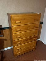 Front view of the vintage wooden dresser showing six drawers and rectangular handles.