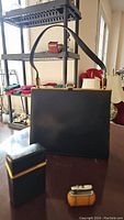 Photo showing black leather purse with gold trim, smoking case and purse lighter foreground