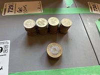 Photo shows multiple stacks of British 1 pound and 2 pound coins in various quantities.