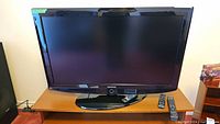 Samsung 40-inch flat screen TV with two remotes on a wooden table, front view.