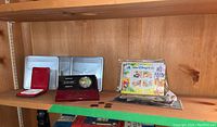 Shelf with open metal tin, red velvet case, burgundy display stand, loose coins and Disney stamps