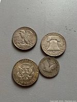 Four coins arranged on a flat surface showing backs and obverse sides with some wear visible.