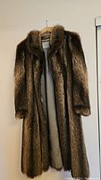 Full front view of vintage raccoon fur coat showing length, fur texture, and silhouette on hanger.