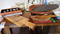 Photo of multiple wood kitchenware items including cutting boards, various wood bowls, and an oval slate board.
