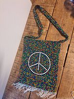 Front view of the beaded purse with peace sign showing full length and strap.