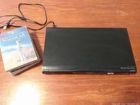 Panasonic Blu-Ray player on wooden surface with stack of five DVDs beside it including Nausicaä DVD on top