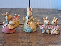 Three detailed ceramic bunny figurines painted in soft pastel shades, shown from the front.