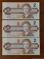 Front view of the three 1986 Canadian two-dollar bills showing Queen Elizabeth II and denominations.