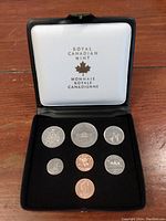Full view of seven Canadian coins in black Royal Canadian Mint presentation case with white interior lining and gold logo text.