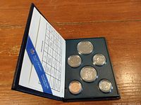 Full open binder showing seven Canadian coins in individual holders, with a chart inside cover describing coins and their values