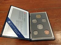 Complete set of 7 uncirculated 1988 Canadian coins displayed inside original blue fold-out presentation case with an informational card on the left.