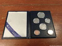 Full view of the open navy blue case containing six Canadian coins in protective capsules and a white cloth flap with logo ribbon.