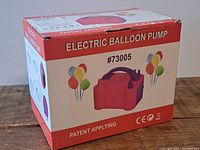 Front and side view of the cardboard box for the electric balloon pump, showing product image, model number #73005 and colorful balloon graphics.