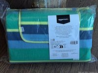Front view of the picnic blanket folded and packaged showing label with product details and Amazon Basics brand.