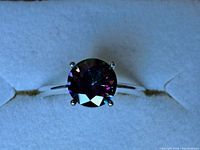 Close-up view of round faceted mystic topaz stone set on a polished sterling silver band.