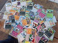 Pile of over 60 assorted Pokemon trading cards showing a variety of Pokemon and energy cards.